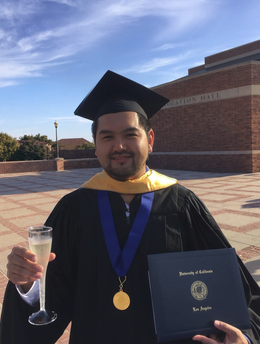 Canybec Sulayman at UCLA Anderson commencement, in cap and gown, holding the University of California diploma